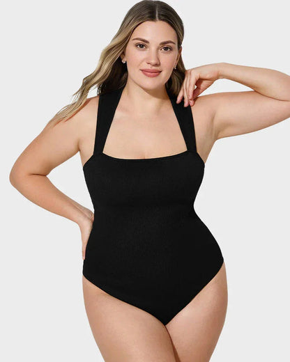Woman wearing black shapewear bodysuit with wide straps, front view on white background.
