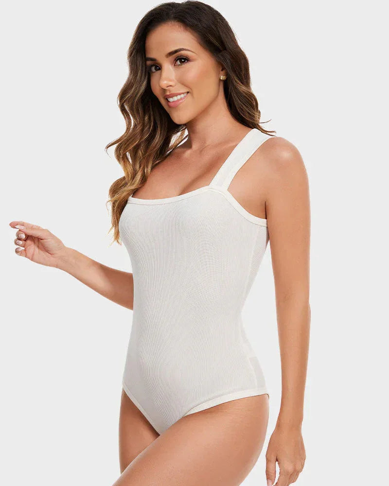 Woman wearing white shapewear bodysuit with wide straps, posing against light background